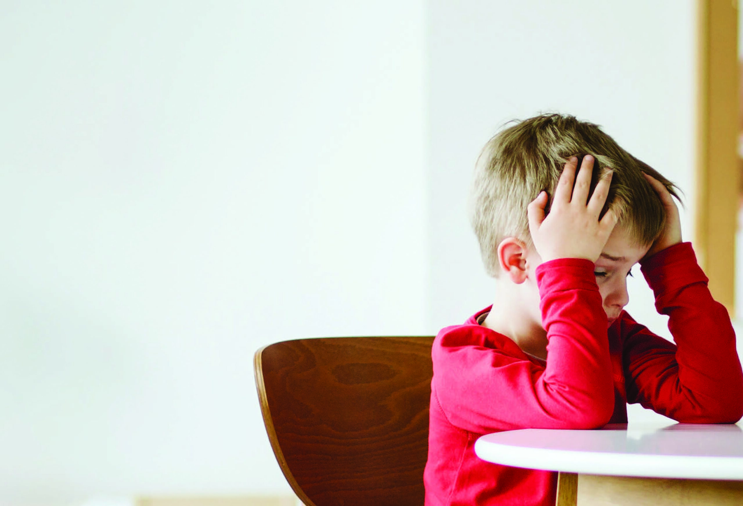 Child sitting at desk with head in hands